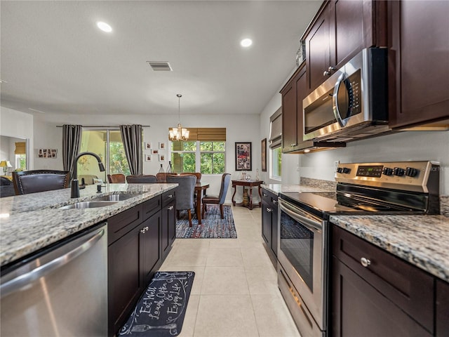 kitchen featuring a sink, stainless steel appliances, a notable chandelier, visible vents, and light stone countertops