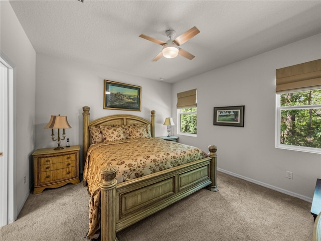 carpeted bedroom featuring a textured ceiling, baseboards, and a ceiling fan