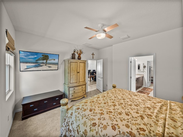 bedroom with ensuite bathroom, baseboards, visible vents, ceiling fan, and light carpet