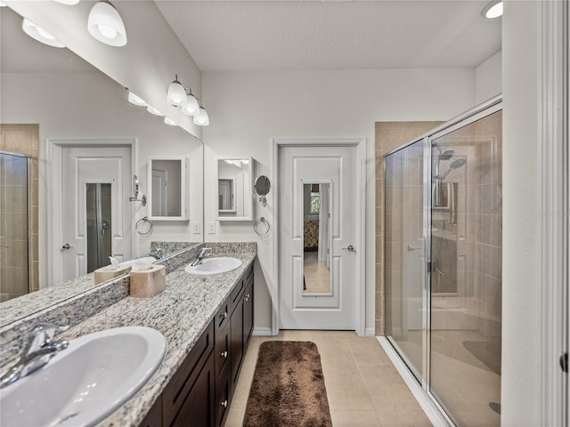 bathroom with double vanity, tile patterned floors, a stall shower, and a sink