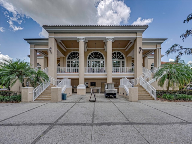 rear view of property featuring a porch, stucco siding, and stairs