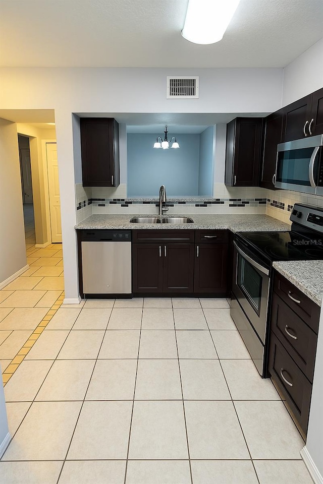 kitchen featuring backsplash, visible vents, appliances with stainless steel finishes, a sink, and a notable chandelier
