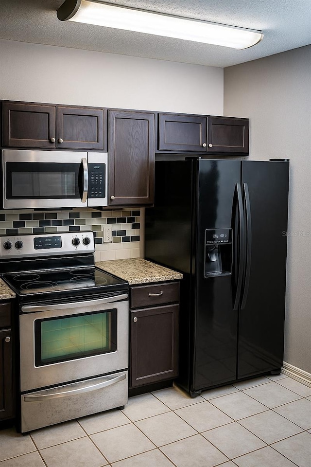 kitchen featuring decorative backsplash, light tile patterned floors, dark brown cabinetry, and stainless steel appliances
