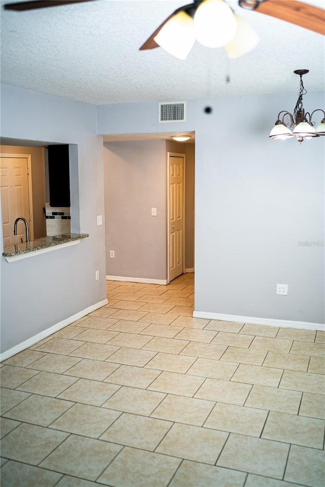 empty room featuring a ceiling fan, a textured ceiling, visible vents, a sink, and baseboards