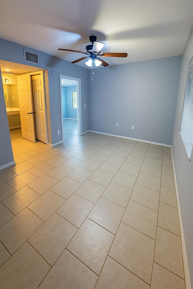 interior space with light tile patterned floors, baseboards, a ceiling fan, and visible vents