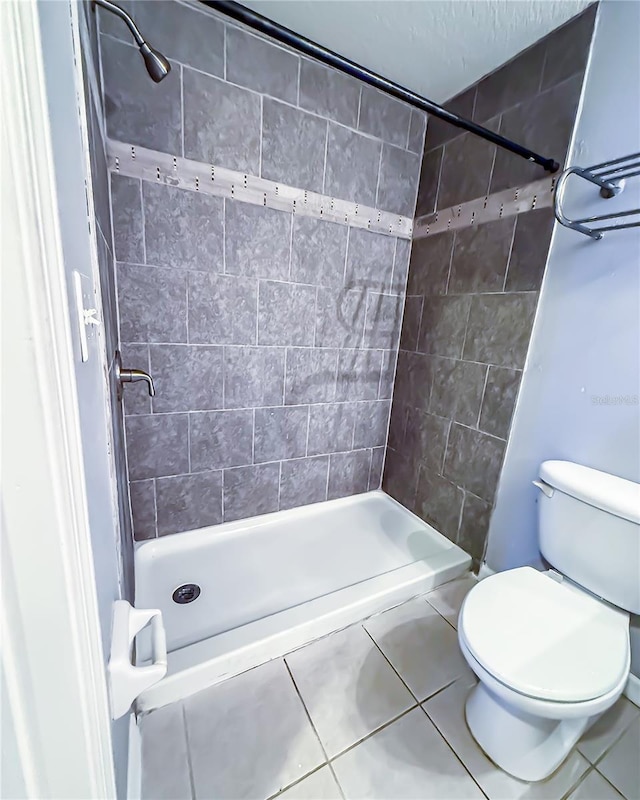 bathroom featuring toilet, tile patterned floors, and a shower stall