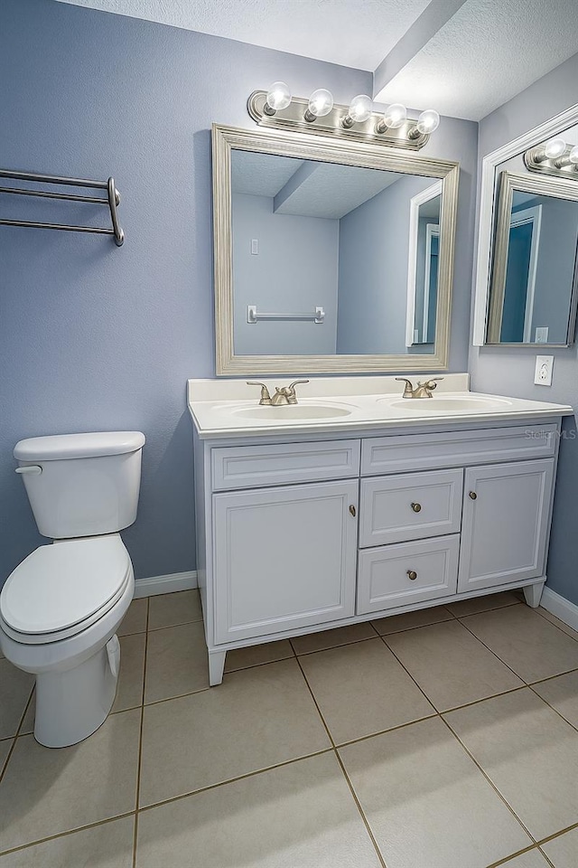 bathroom featuring double vanity, a sink, tile patterned floors, and toilet
