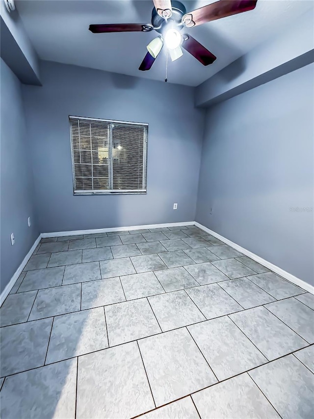 tiled spare room featuring baseboards and ceiling fan