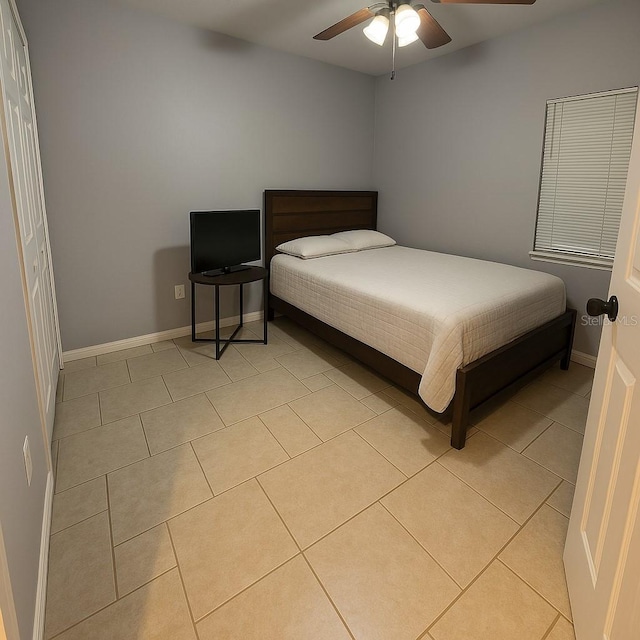 bedroom featuring a ceiling fan, baseboards, and light tile patterned floors