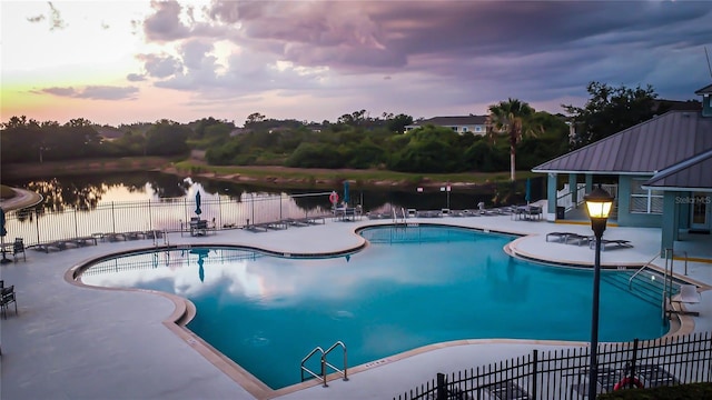pool featuring fence, a water view, and a patio area