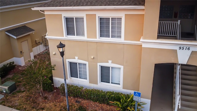 view of property exterior with a balcony, roof with shingles, and stucco siding