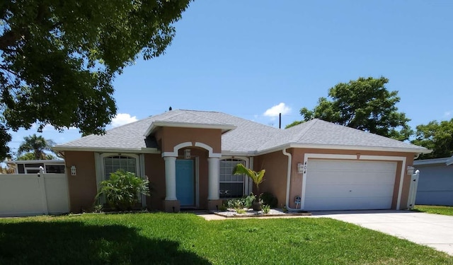 ranch-style house with fence, an attached garage, a front lawn, stucco siding, and driveway