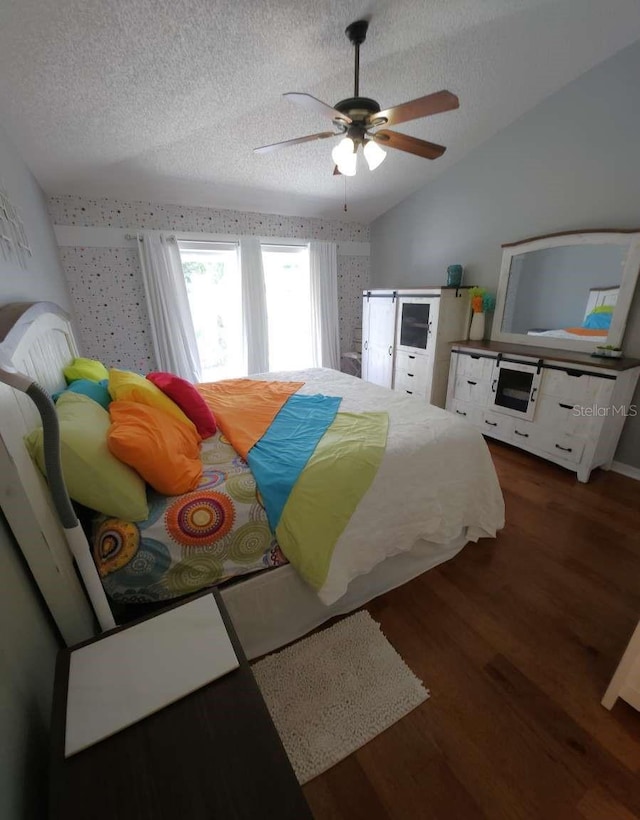 bedroom featuring a ceiling fan, a textured ceiling, lofted ceiling, and wood finished floors