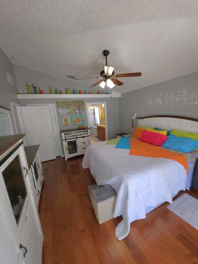 bedroom featuring a ceiling fan, a textured ceiling, lofted ceiling, and wood finished floors