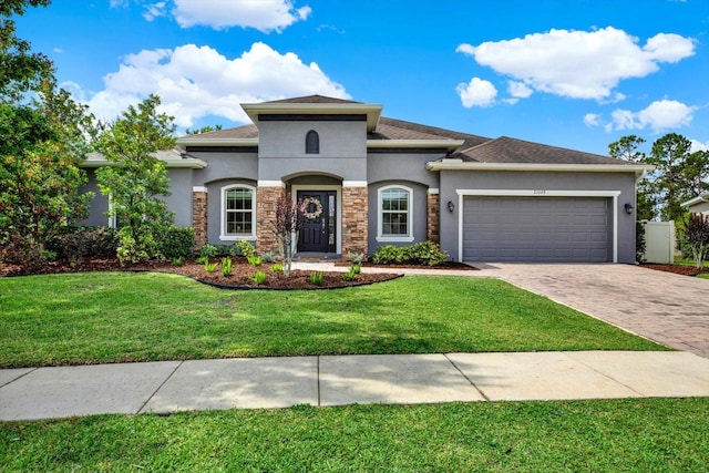 view of front of house with an attached garage, driveway, a front lawn, and stucco siding