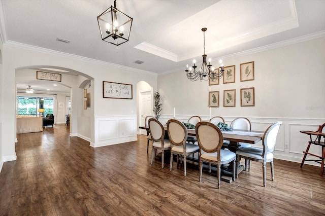 dining room with crown molding, arched walkways, a decorative wall, and dark wood-style floors