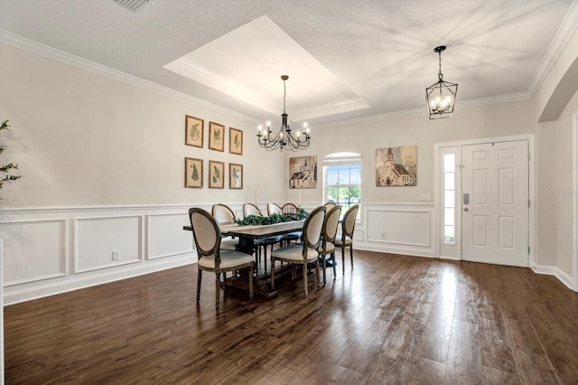 dining space featuring a chandelier, ornamental molding, dark wood finished floors, and a raised ceiling