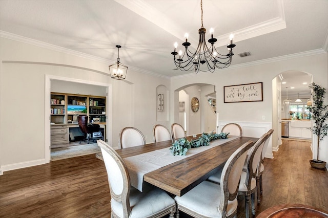dining space with visible vents, crown molding, arched walkways, wood finished floors, and a chandelier