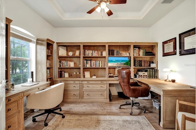 office featuring a raised ceiling, a ceiling fan, wood finished floors, and built in study area