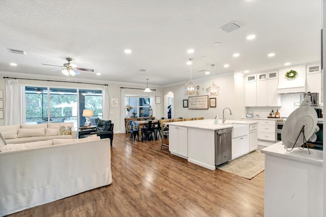 kitchen featuring crown molding, a center island with sink, dishwasher, a sink, and open floor plan