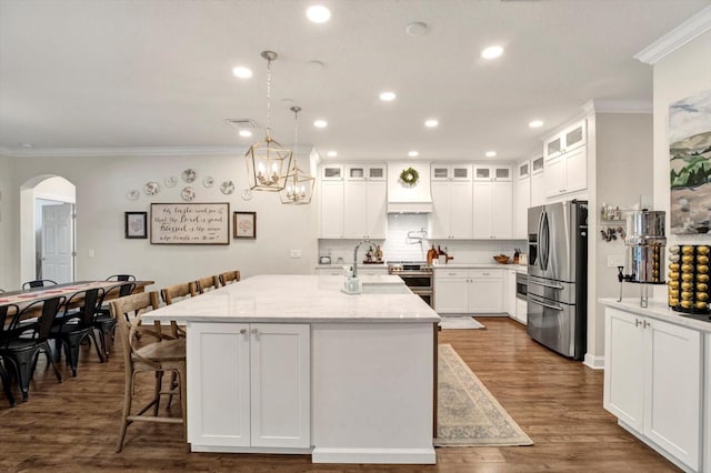 kitchen with appliances with stainless steel finishes, arched walkways, white cabinets, ornamental molding, and recessed lighting