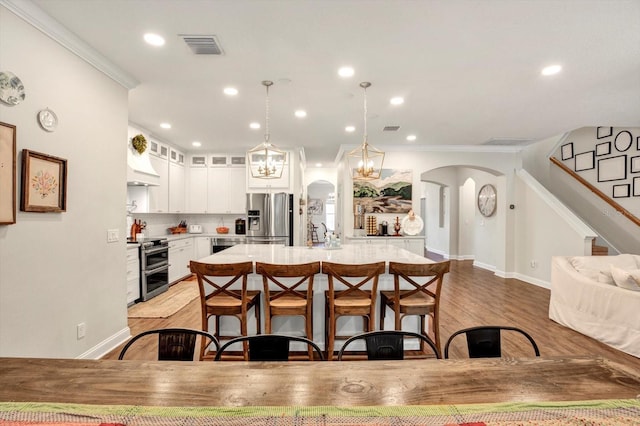 kitchen featuring light countertops, arched walkways, appliances with stainless steel finishes, and ornamental molding
