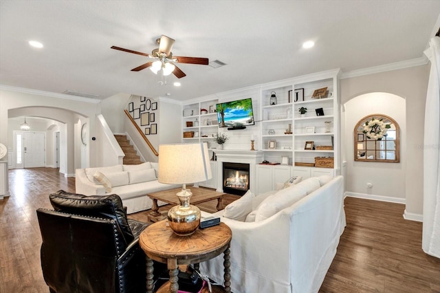 living room with baseboards, arched walkways, a ceiling fan, and ornamental molding