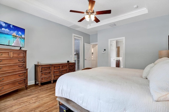 bedroom featuring visible vents, connected bathroom, a raised ceiling, a ceiling fan, and light wood finished floors