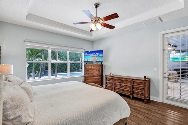 bedroom featuring dark wood-style flooring, access to outside, a tray ceiling, visible vents, and ornamental molding