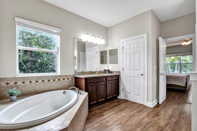 ensuite bathroom featuring connected bathroom, wood finished floors, a bath, and vanity
