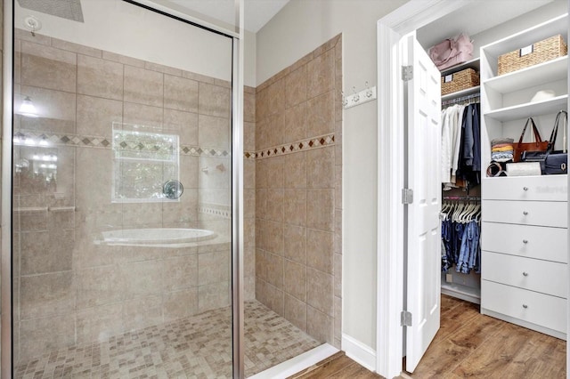 bathroom with a tile shower, wood finished floors, and a spacious closet