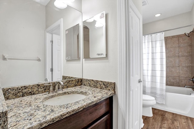 bathroom with vanity, shower / tub combo with curtain, visible vents, wood finished floors, and toilet