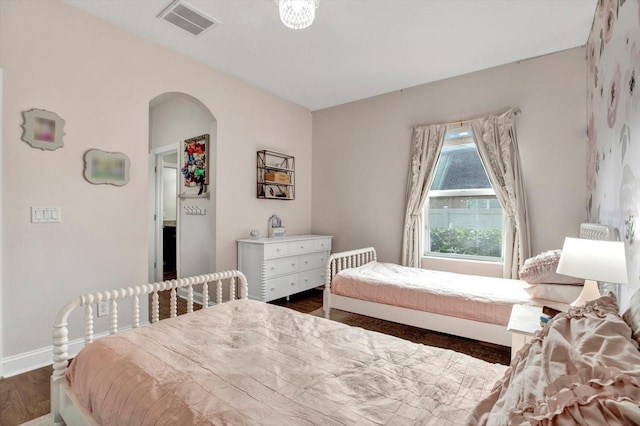 bedroom featuring arched walkways, baseboards, dark wood finished floors, and visible vents