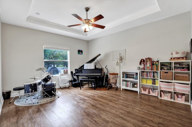 living area with a raised ceiling, ornamental molding, a ceiling fan, and wood finished floors