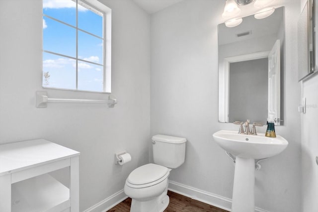 bathroom featuring toilet, baseboards, plenty of natural light, and wood finished floors