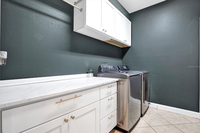 laundry area featuring cabinet space, baseboards, light tile patterned floors, and washer and dryer