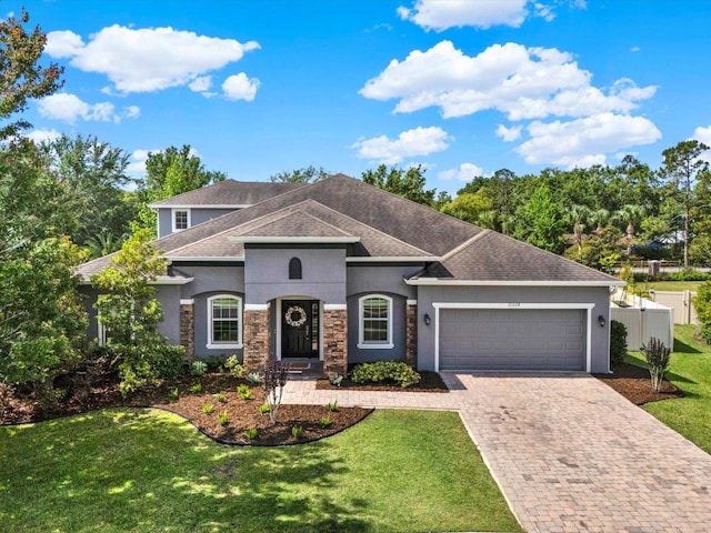 view of front of property featuring fence, a garage, stucco siding, a front yard, and decorative driveway