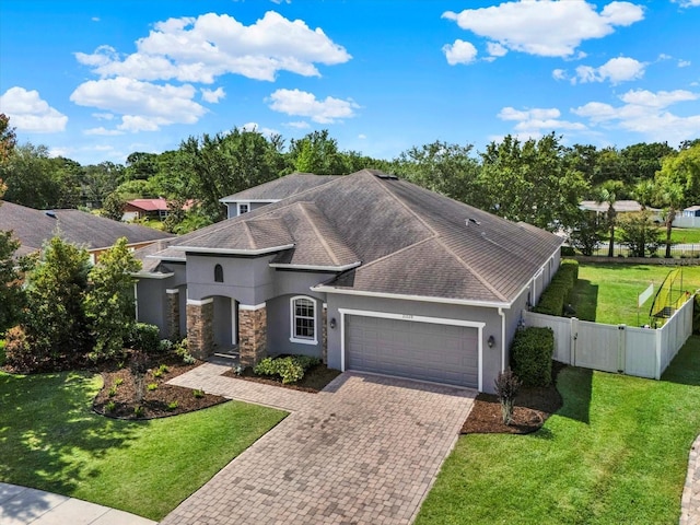 view of front facade with fence, an attached garage, stucco siding, a gate, and decorative driveway