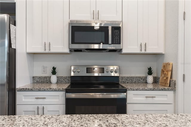 14404 SW 19th Pl, Ocala, FL 34481 - kitchen with light stone counters, white cabinetry, and stainless steel appliances