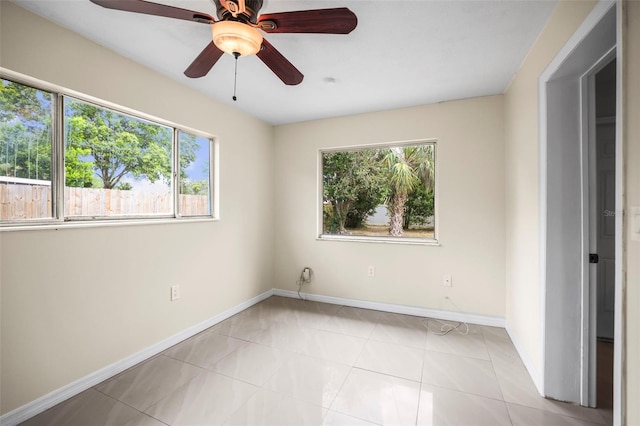 unfurnished room with plenty of natural light, baseboards, ceiling fan, and light tile patterned flooring