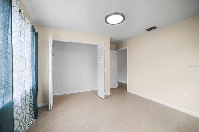 unfurnished bedroom featuring visible vents, baseboards, light tile patterned floors, and a closet