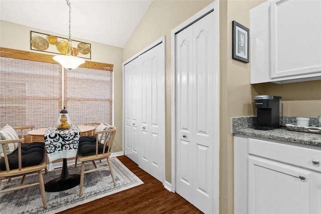 dining space with vaulted ceiling and dark wood-style flooring