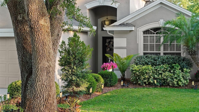 doorway to property featuring a lawn, stucco siding, and a garage
