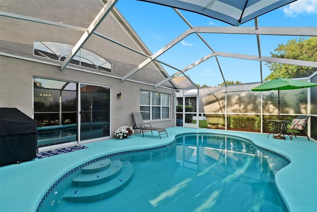 outdoor pool with grilling area, glass enclosure, and a patio area