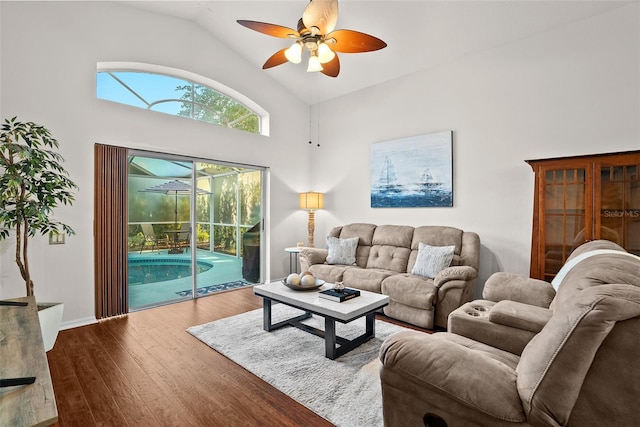 living area with baseboards, a ceiling fan, high vaulted ceiling, and wood finished floors