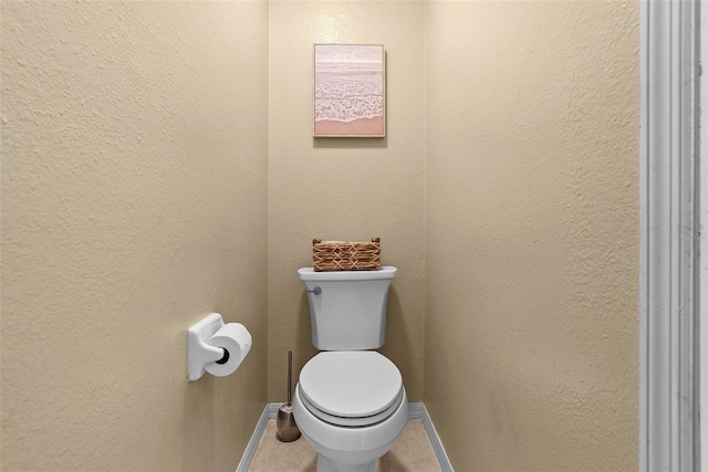 bathroom featuring baseboards, tile patterned flooring, and toilet