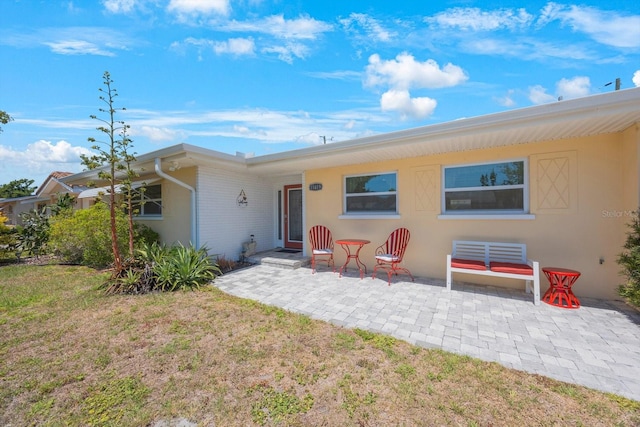 rear view of property with a lawn and a patio