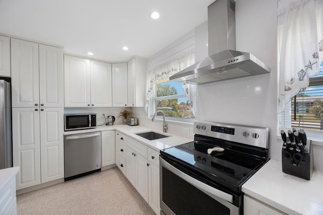 kitchen featuring white cabinetry, appliances with stainless steel finishes, a sink, and wall chimney exhaust hood