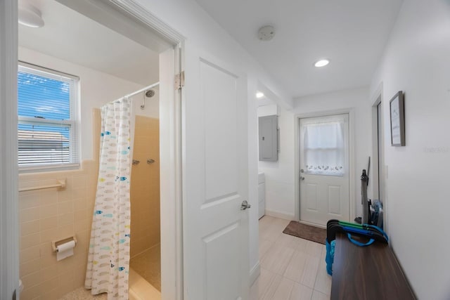 bathroom featuring tile patterned floors, electric panel, a stall shower, and tile walls