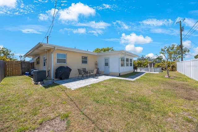 back of property with a patio, a fenced backyard, stucco siding, central AC unit, and a lawn